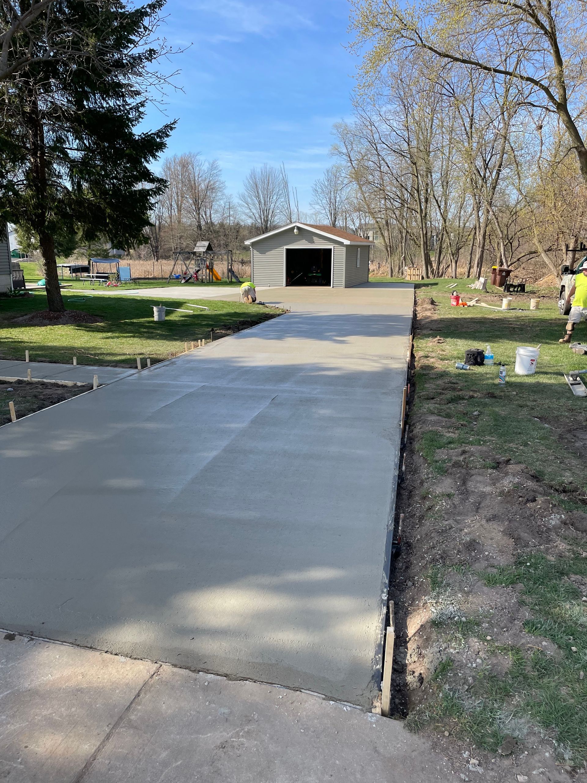 A concrete driveway is being built next to a garage.