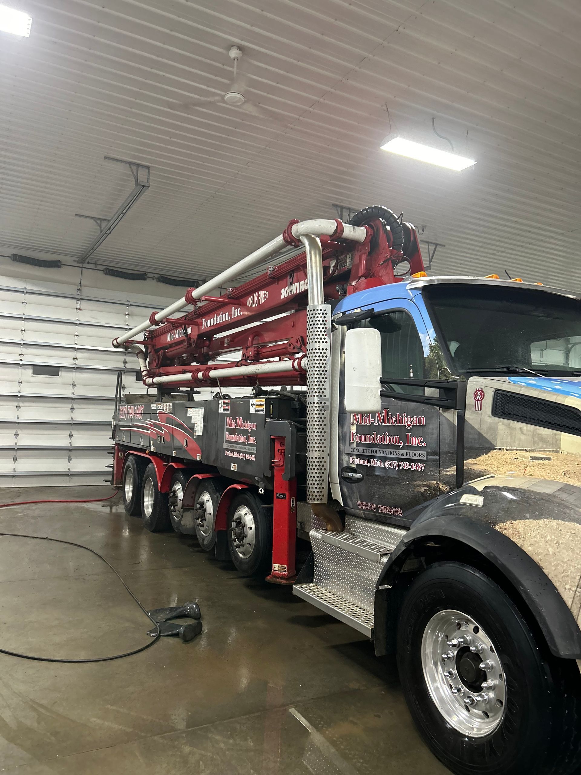 A large concrete pump truck is parked in a garage.