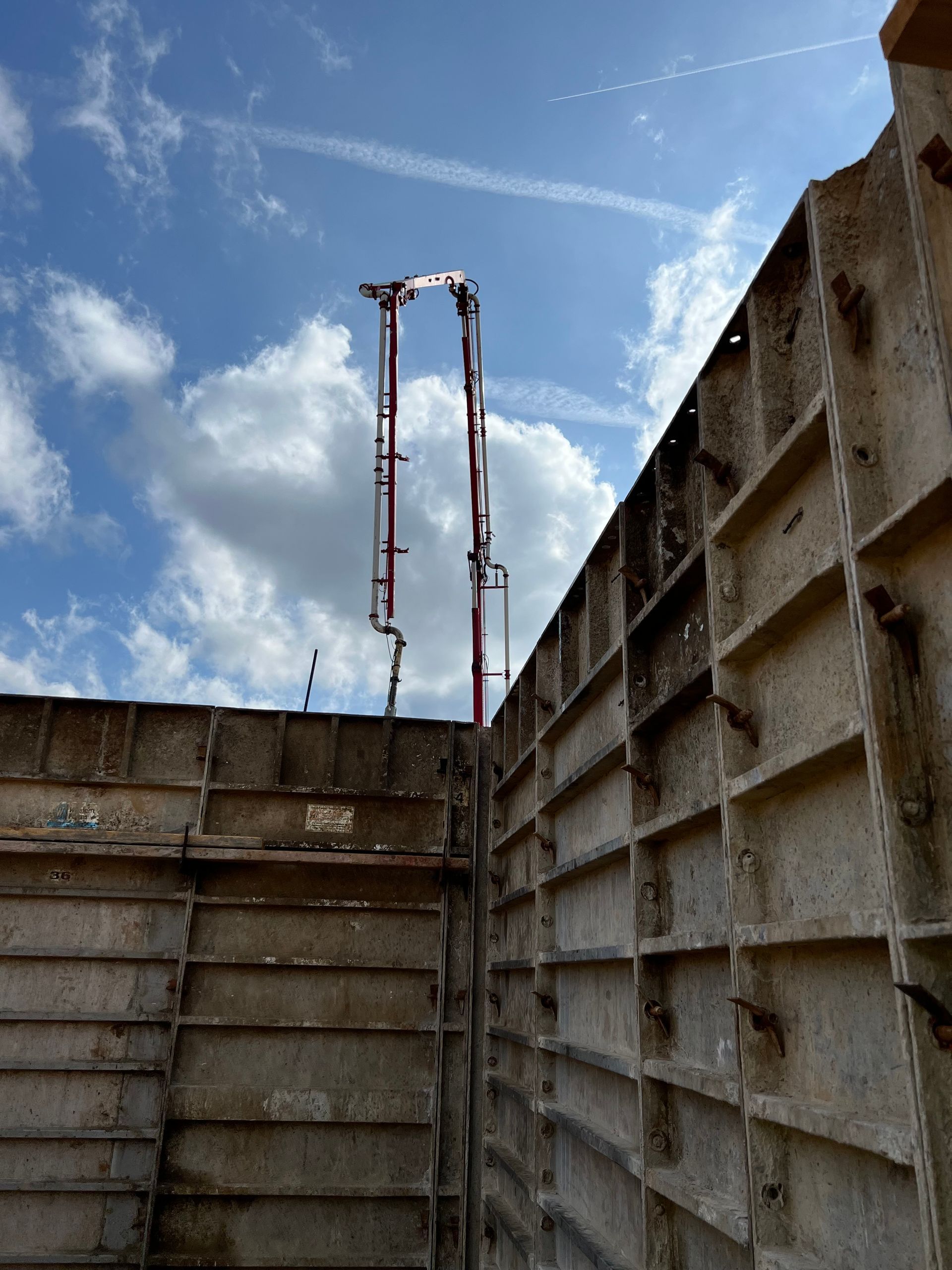 A concrete pump is being used to pour concrete into a wall