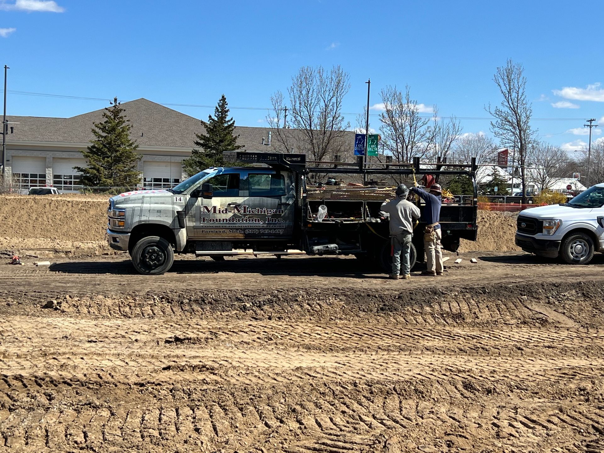 A group of people are standing next to a truck in a dirt field.