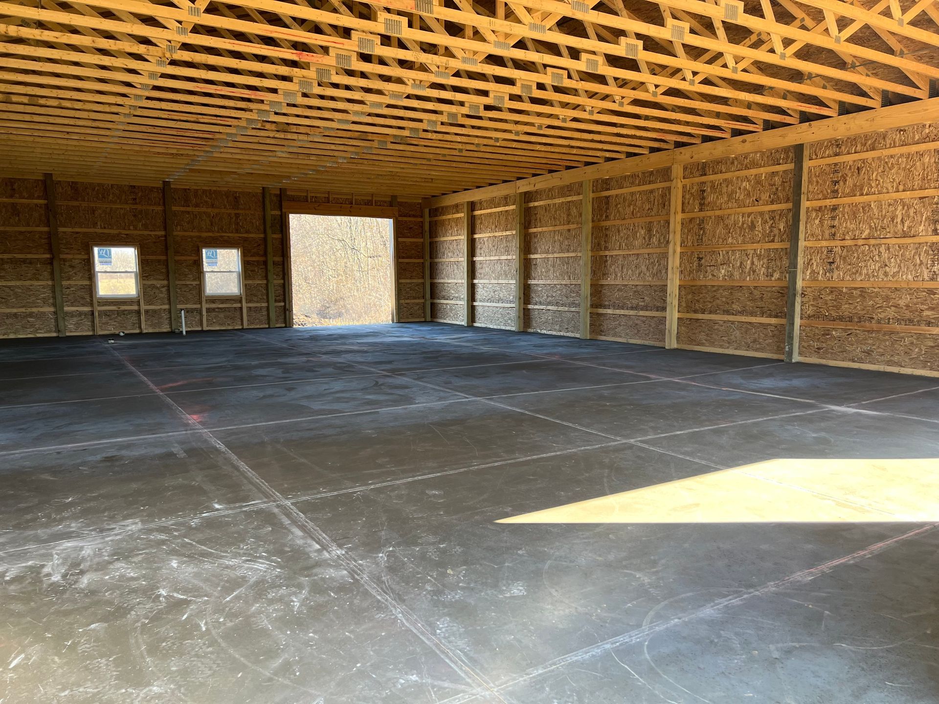 A large empty building with a wooden roof and a concrete floor.