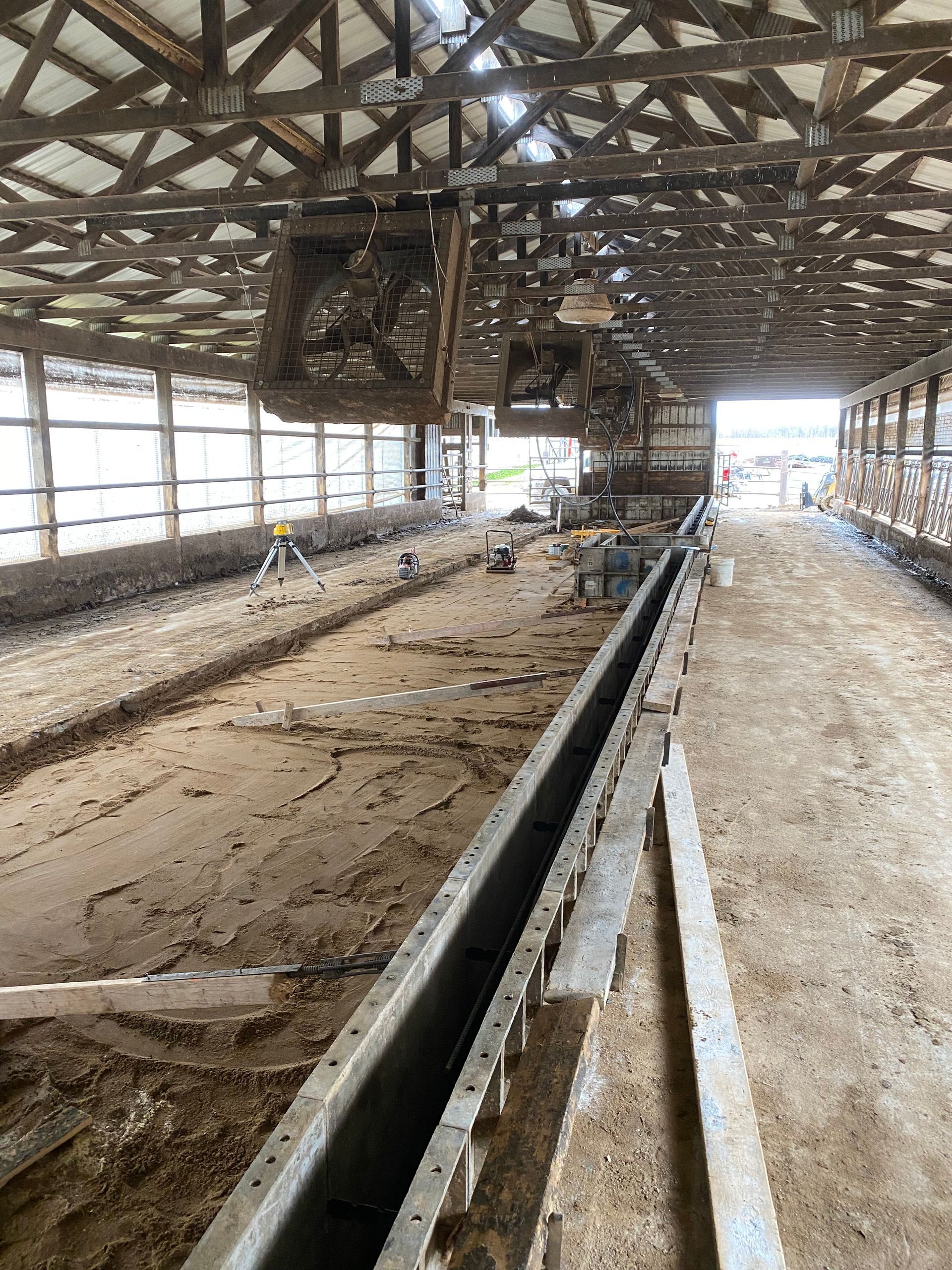 The inside of a barn with a lot of dirt on the floor.