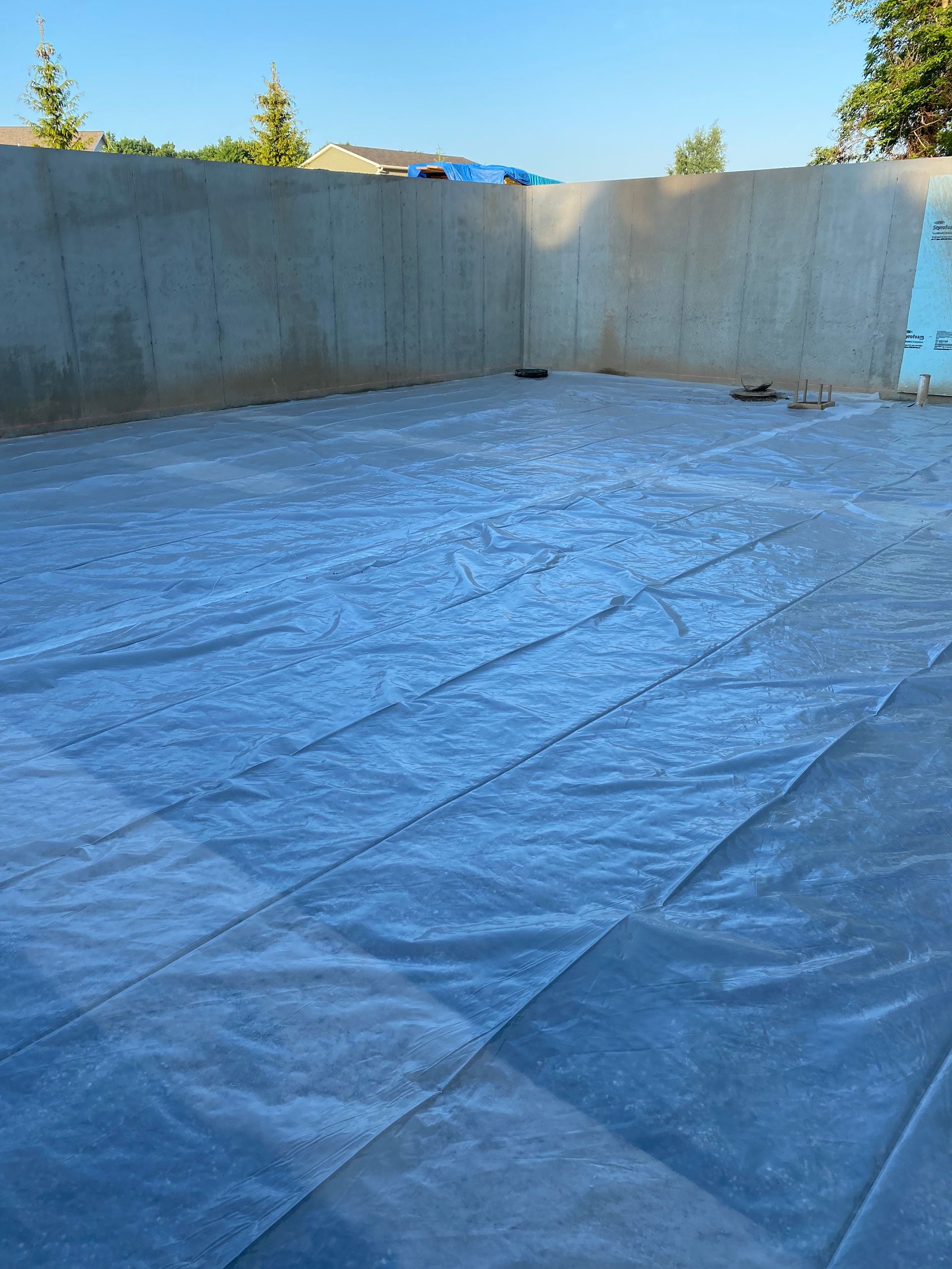 A concrete wall with a tarp on the ground in front of it.