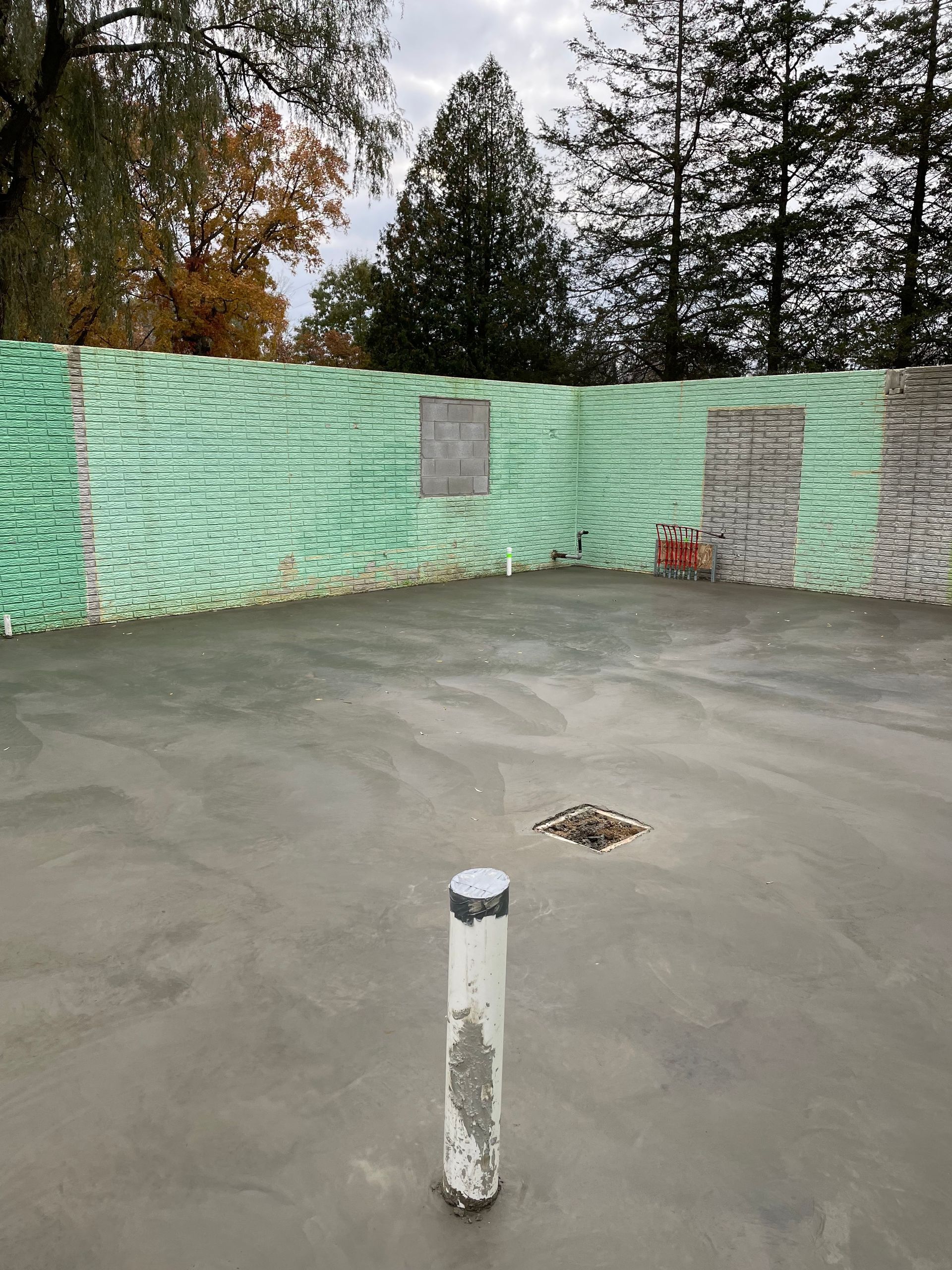 A white pipe is sitting in the middle of a concrete floor.
