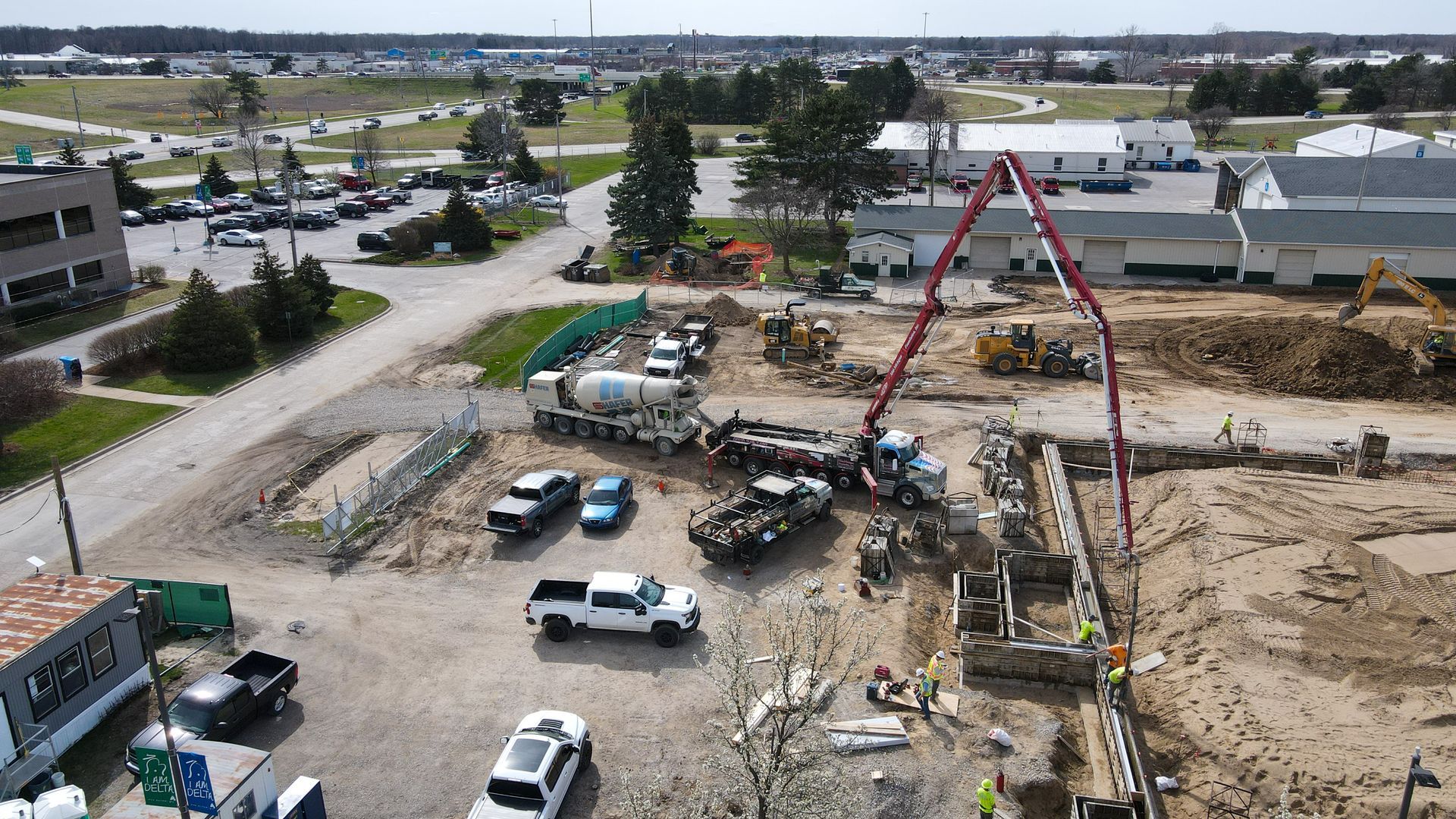 An aerial view of a construction site with trucks and a concrete pump.