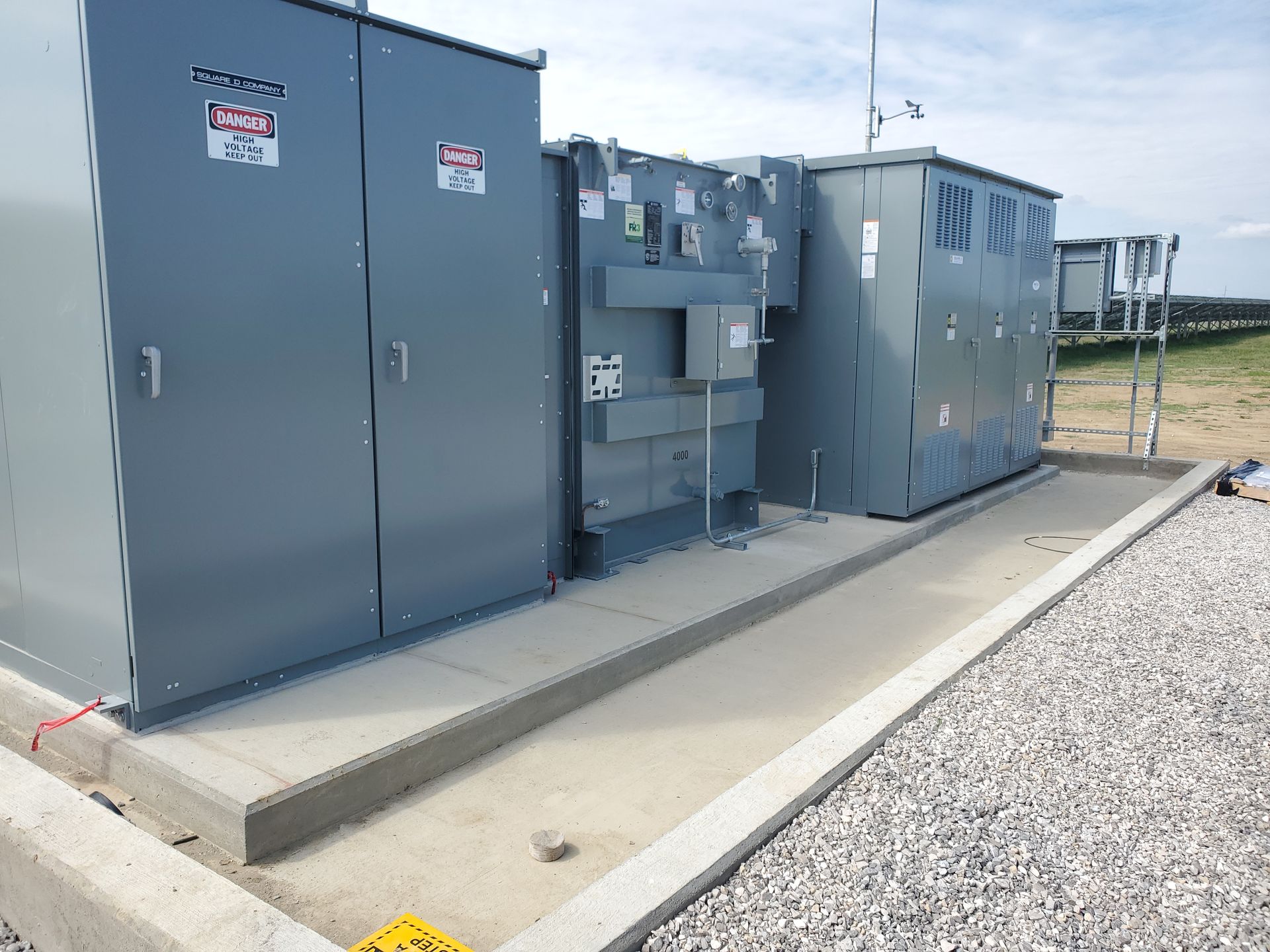 A bunch of electrical equipment is sitting on top of a gravel lot.