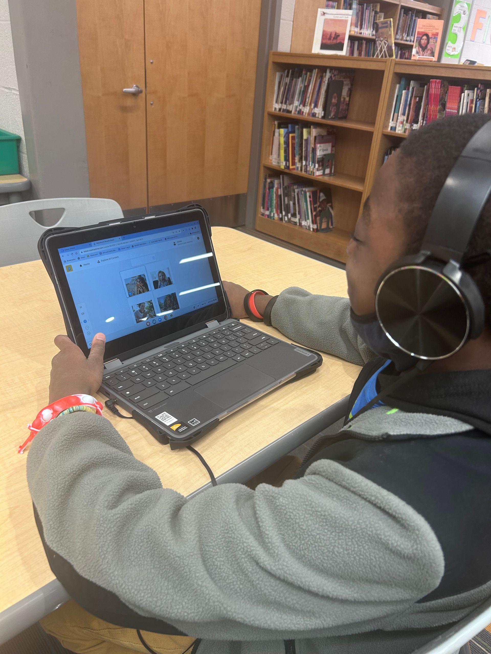 Heart of the Schools student using a laptop with headphones in a library.