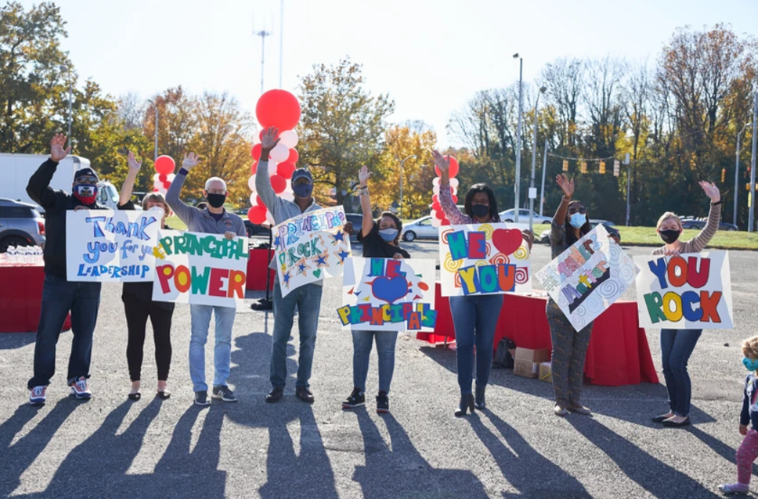 Drive Thur for You Event - People holding signs with messages, outdoors. Some have masks, red balloons, and raised arms.