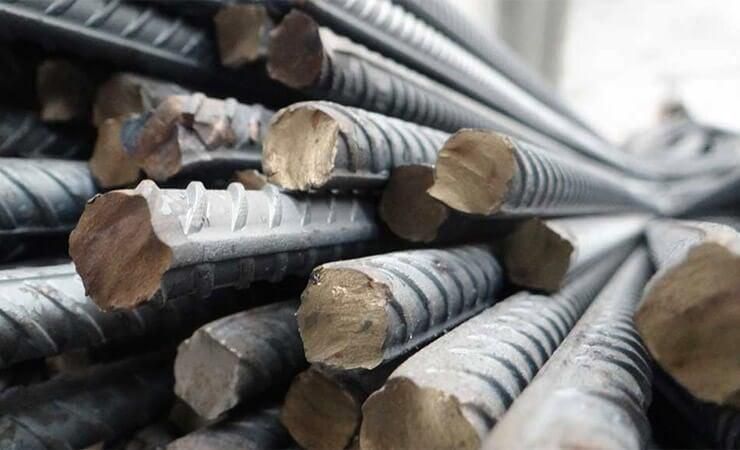 Primer plano de una pila de barras de refuerzo de acero con extremos cortados y ásperos.