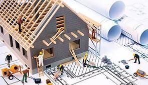 Casa en miniatura en construcción con planos y maquetas de trabajadores.