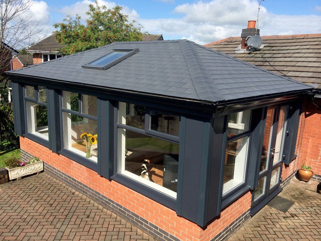 A conservatory with a slate roof and a lot of windows.