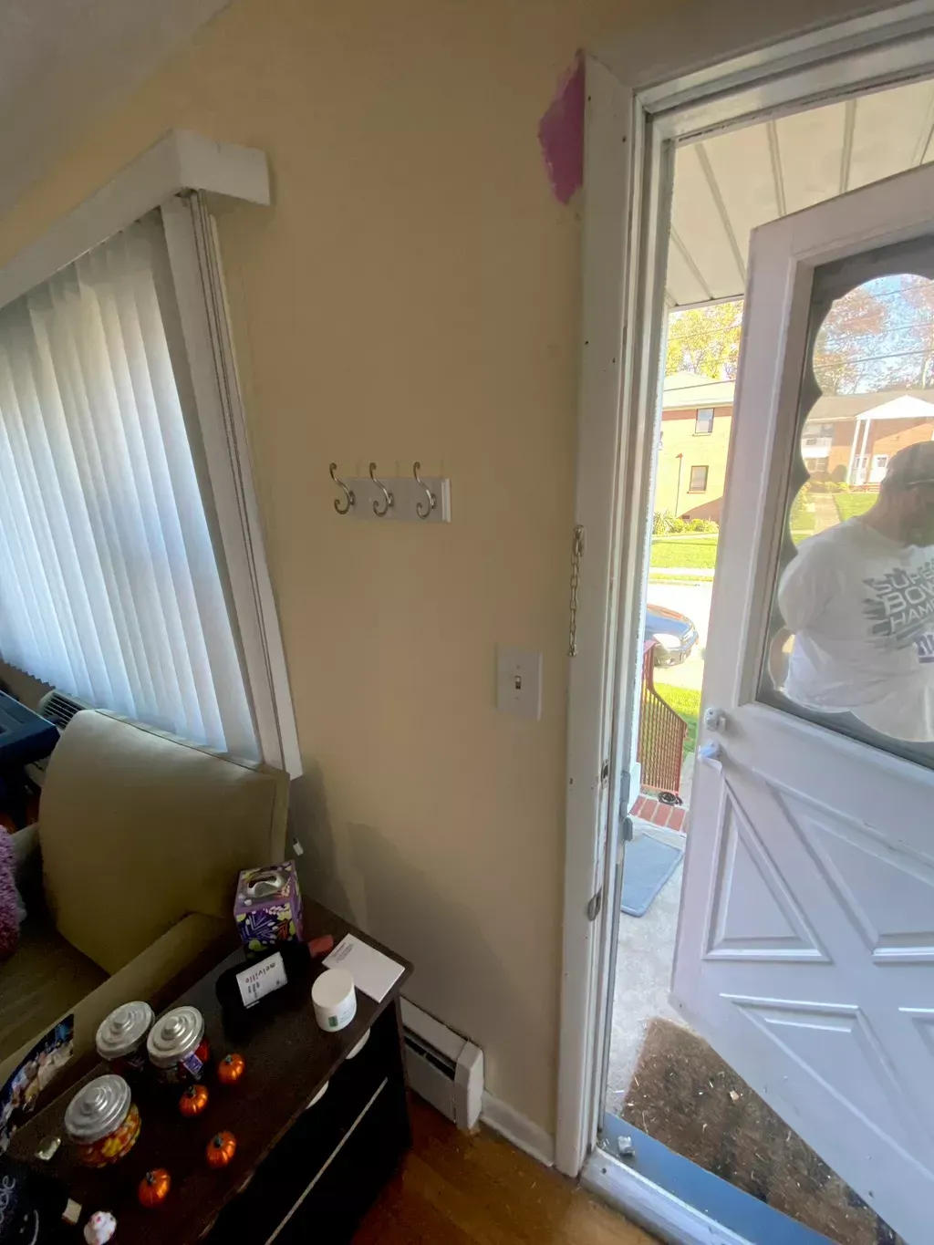 Interior view of a home: tan walls, white trim around the doorway, a person in the doorway.