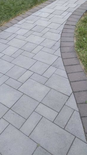 Brick pathway winding through green grass, light gray paving stones.