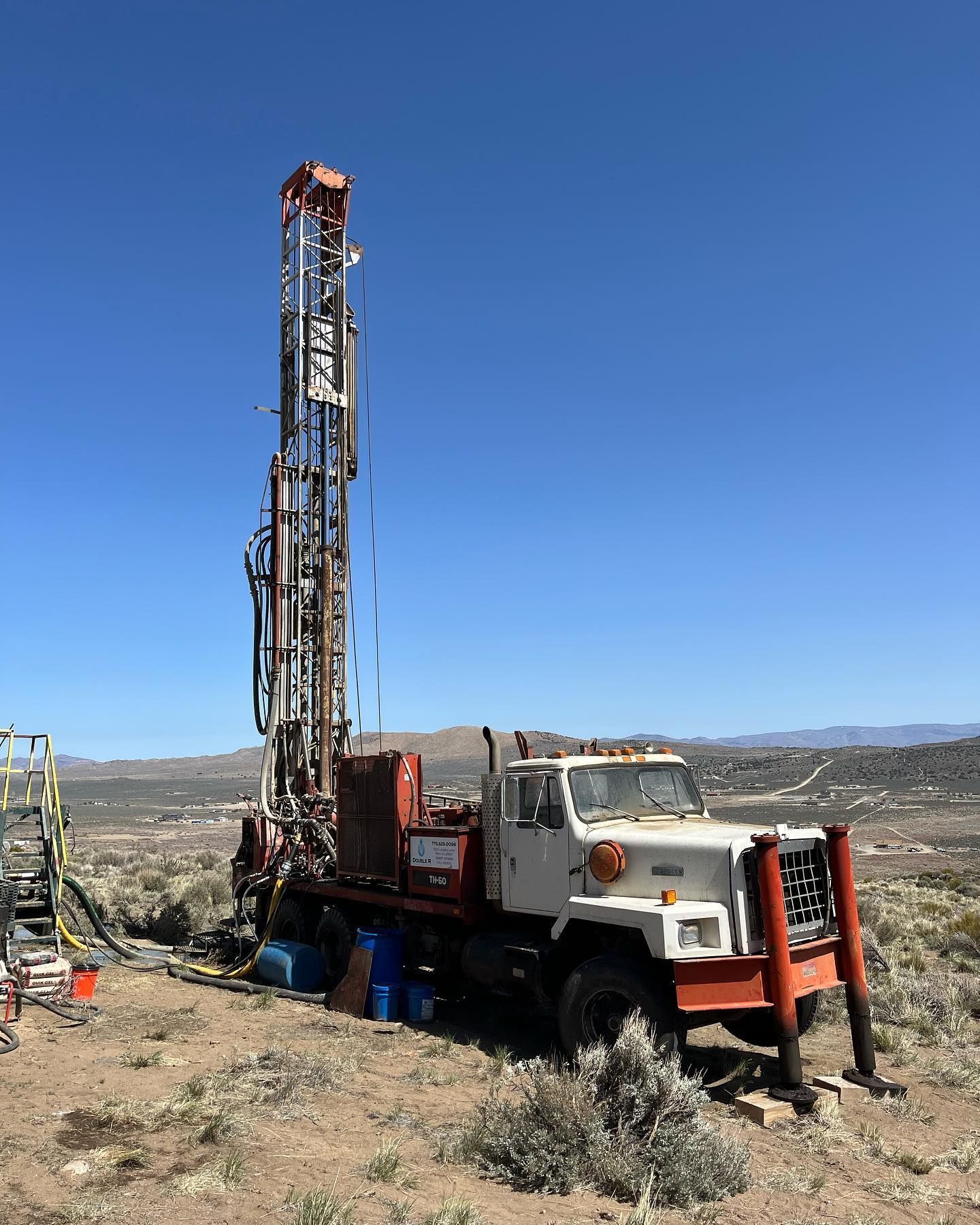 Drilling rig on a truck in a desert landscape under a clear blue sky.