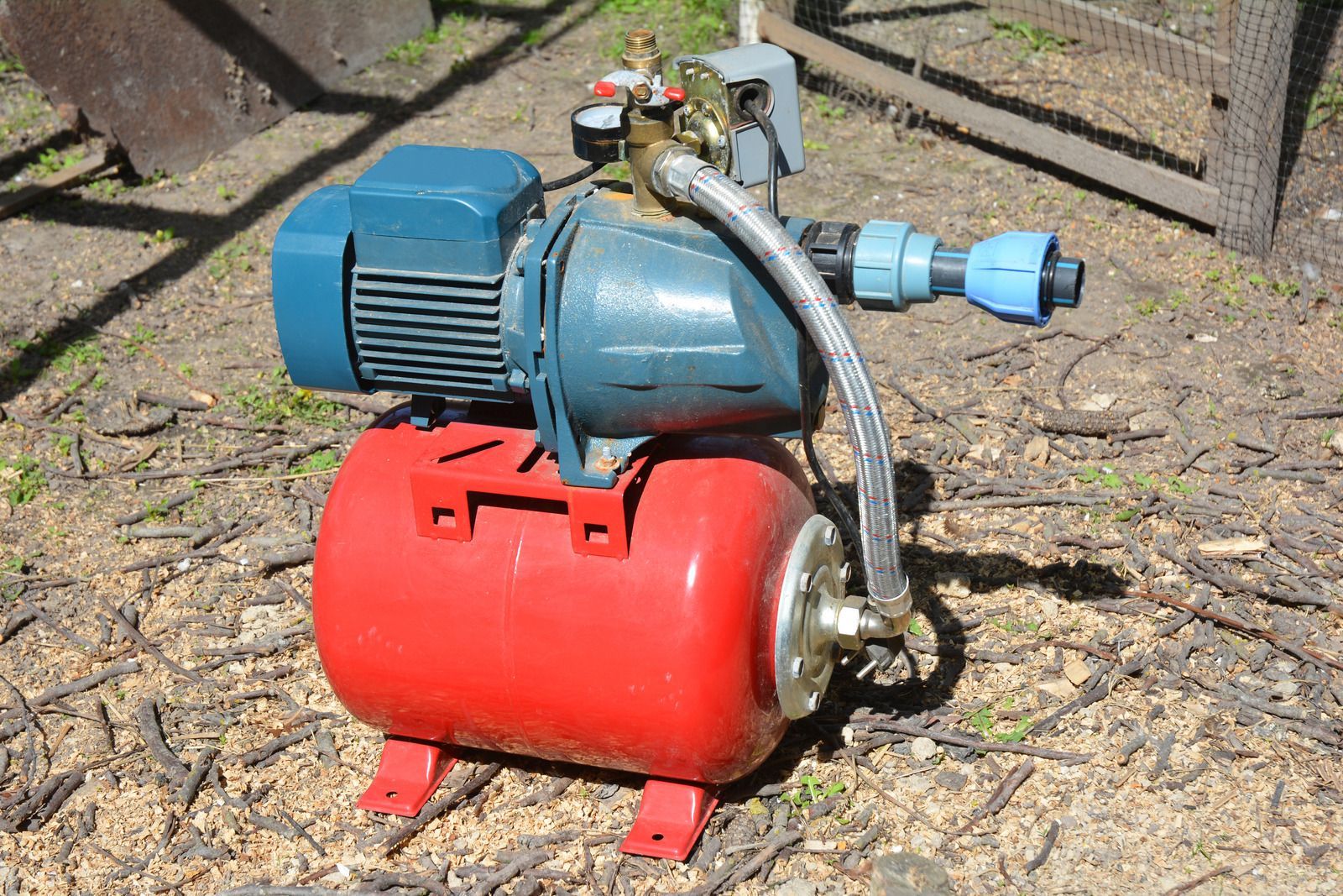 Red water pump with a blue motor and tank, outdoors.