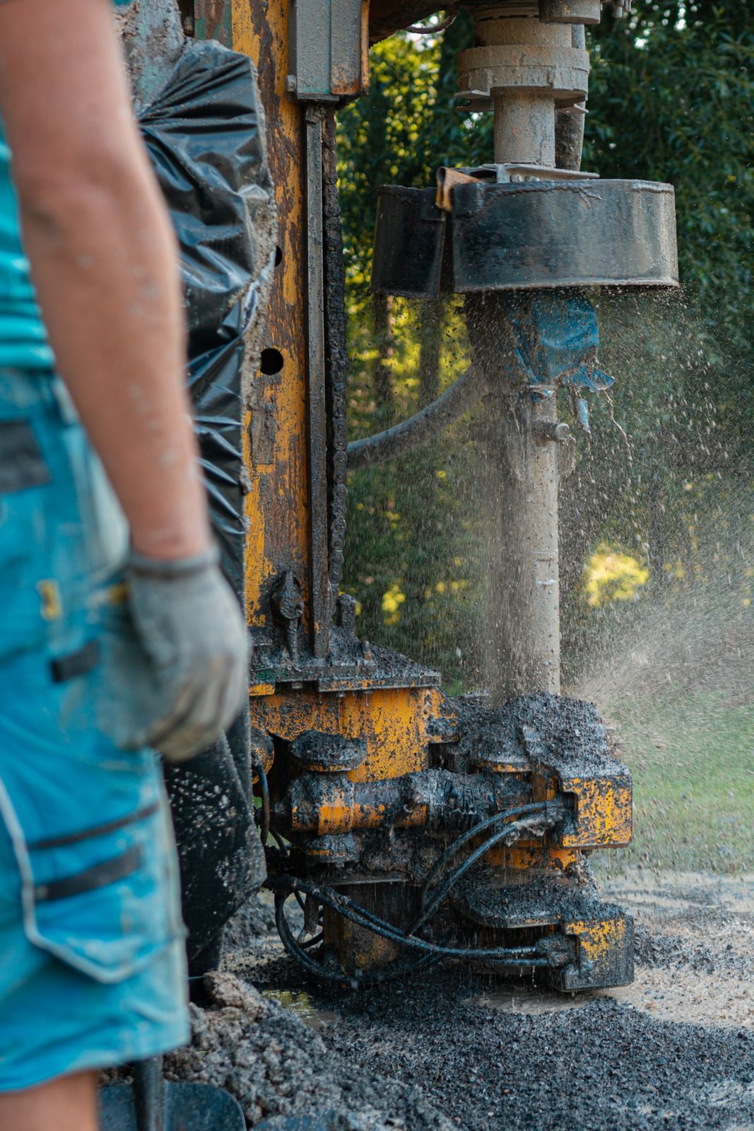 Person operating drilling equipment, spraying water and mud.