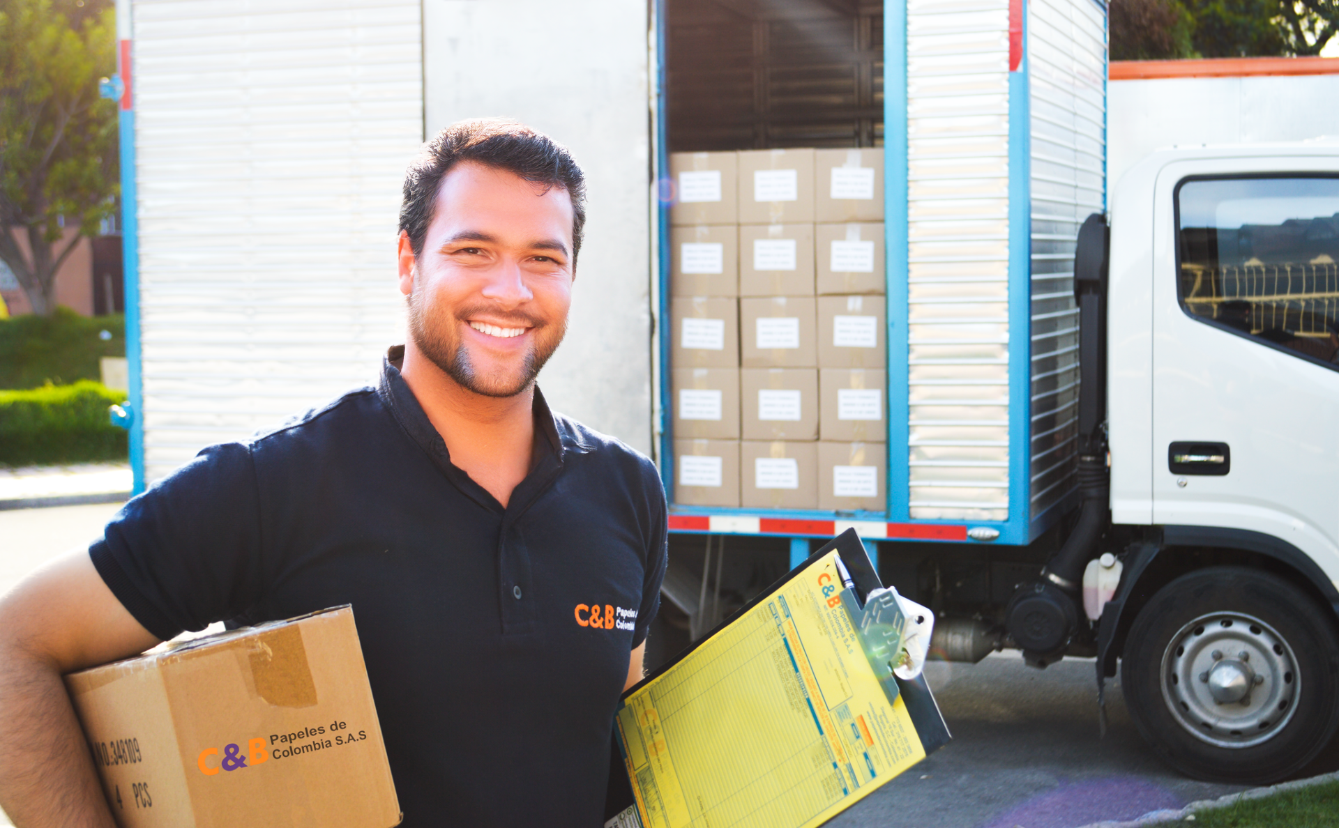 Hombre sosteniendo caja con camion detras
