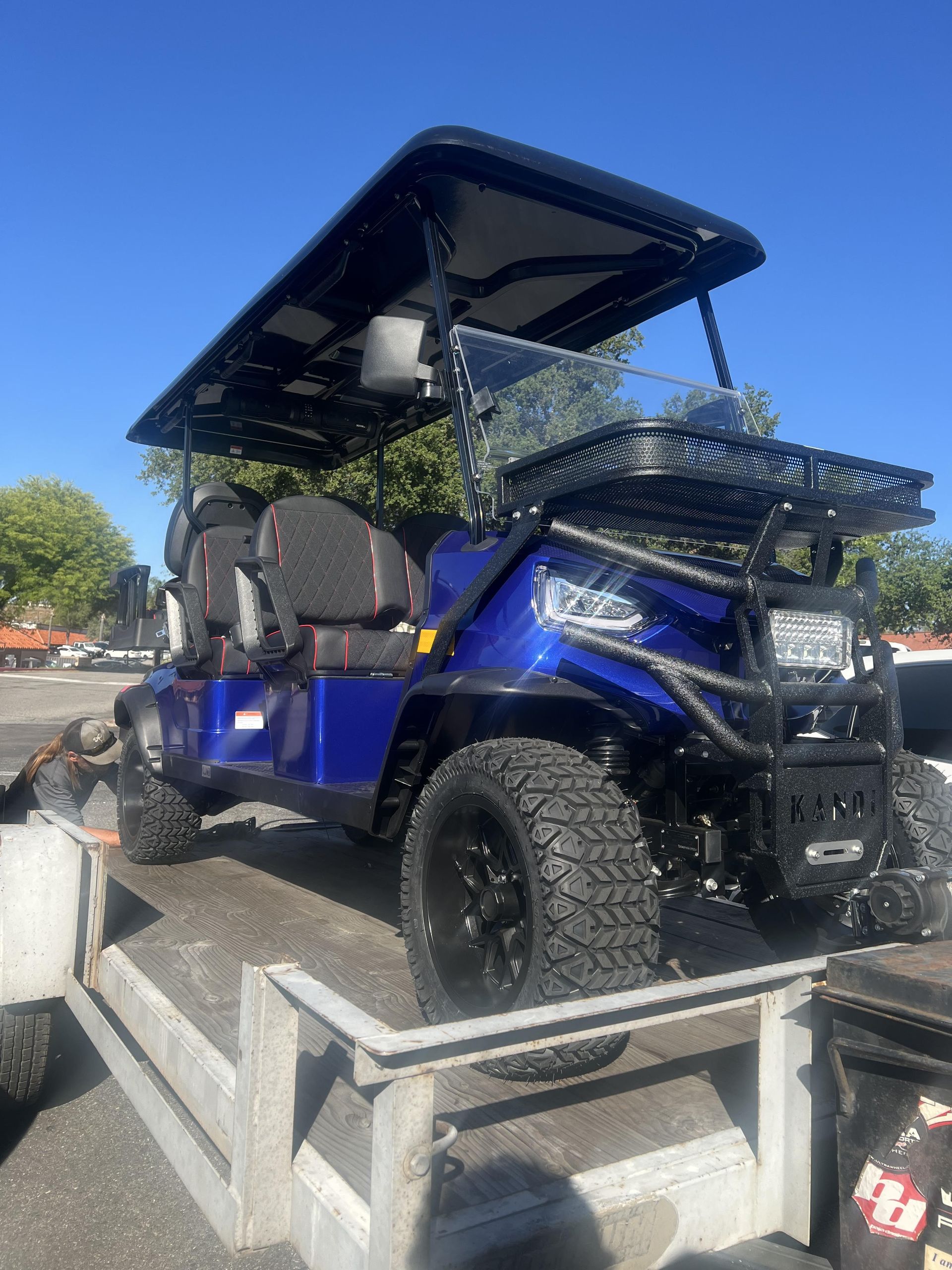 A blue golf cart is parked in a parking lot.