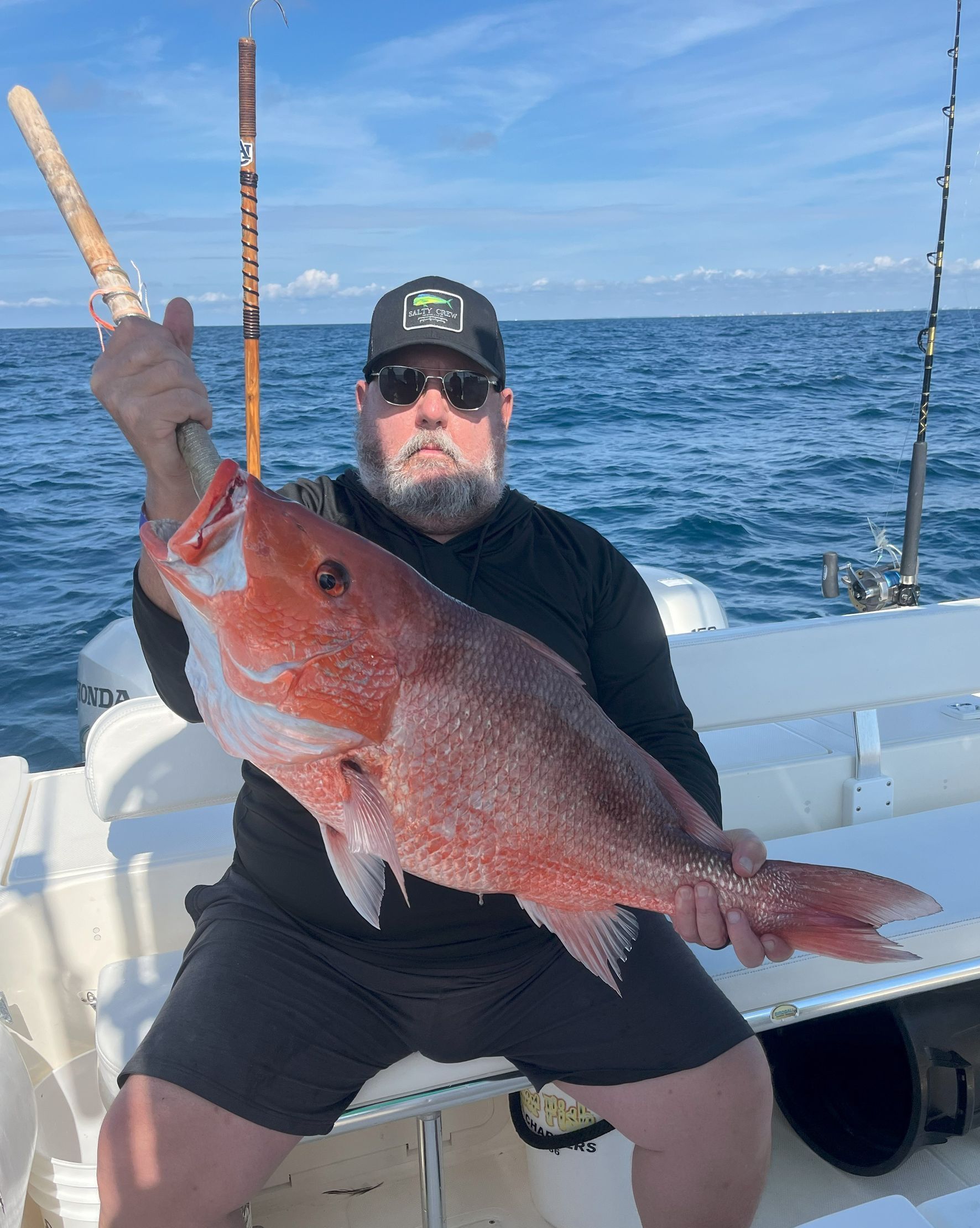 Two men are fishing on a boat with a shark in the water.