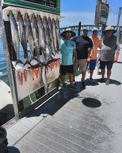 A group of men are standing next to a display of fish on a dock.