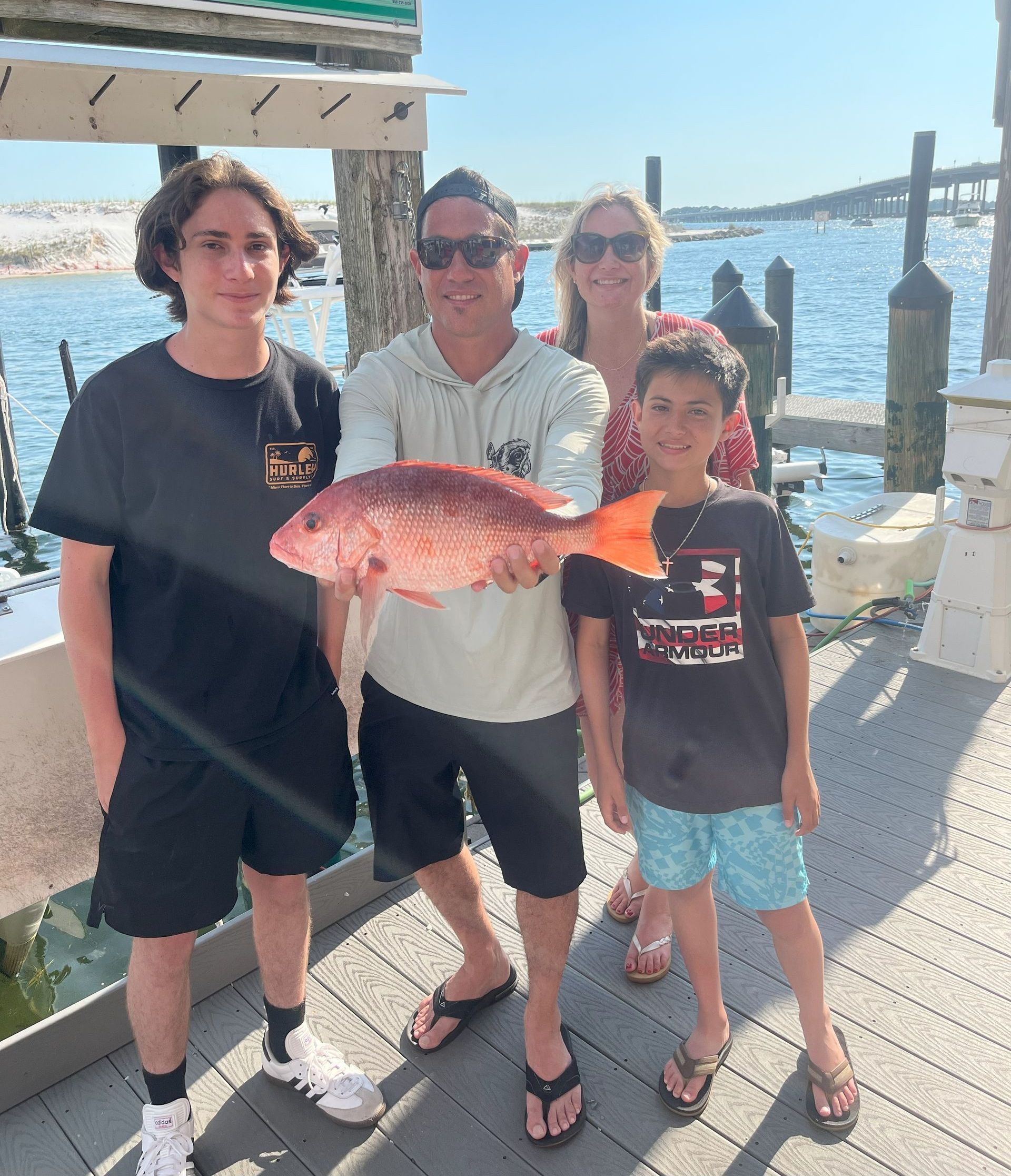 A group of people standing next to each other holding a large fish.