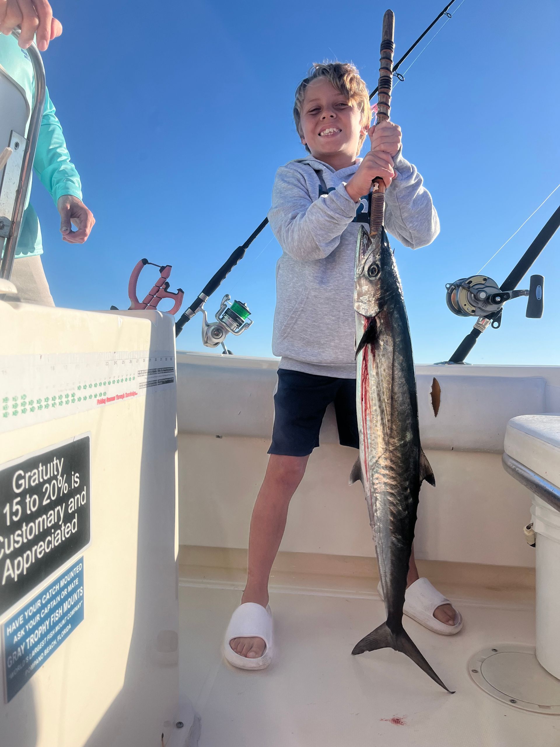 A young boy is holding a large fish on a boat.