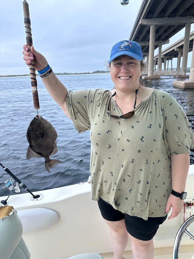 A woman is standing on a boat holding a fish in her hand.