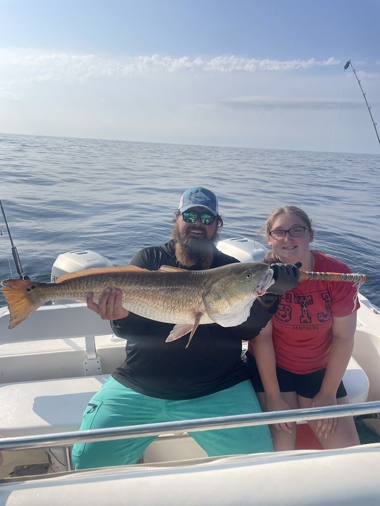 A man and a woman are sitting on a boat holding a large fish.