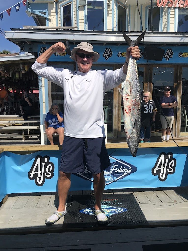 A man is holding a large fish in front of a building.