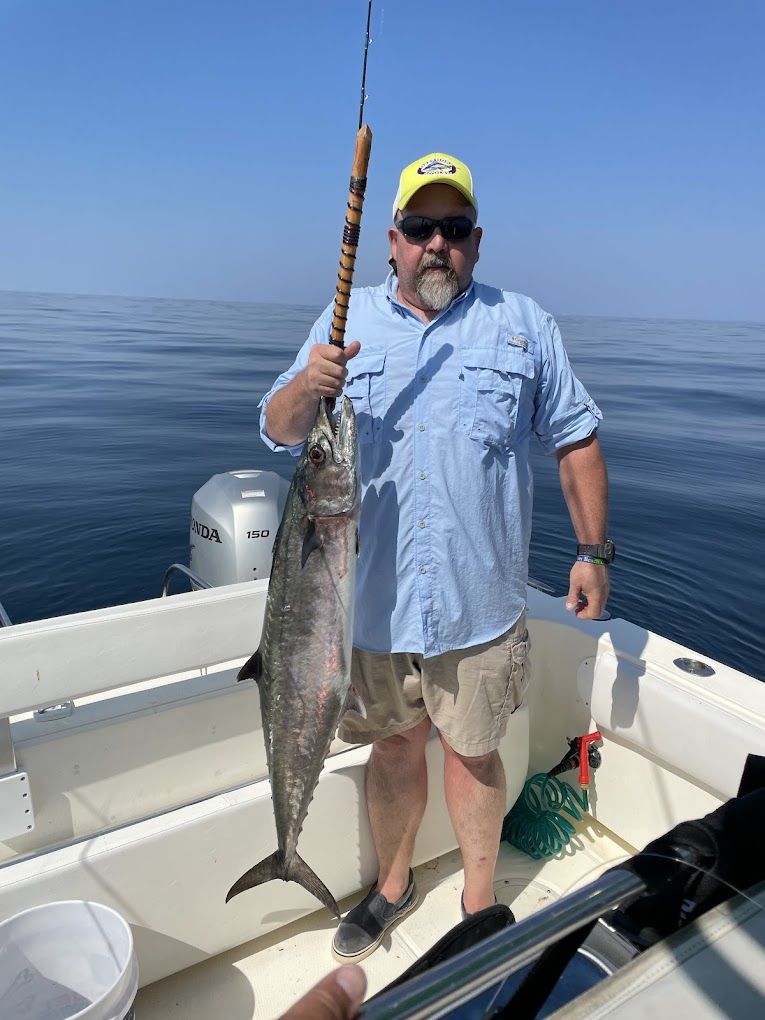 A man is standing on a boat holding a large fish.