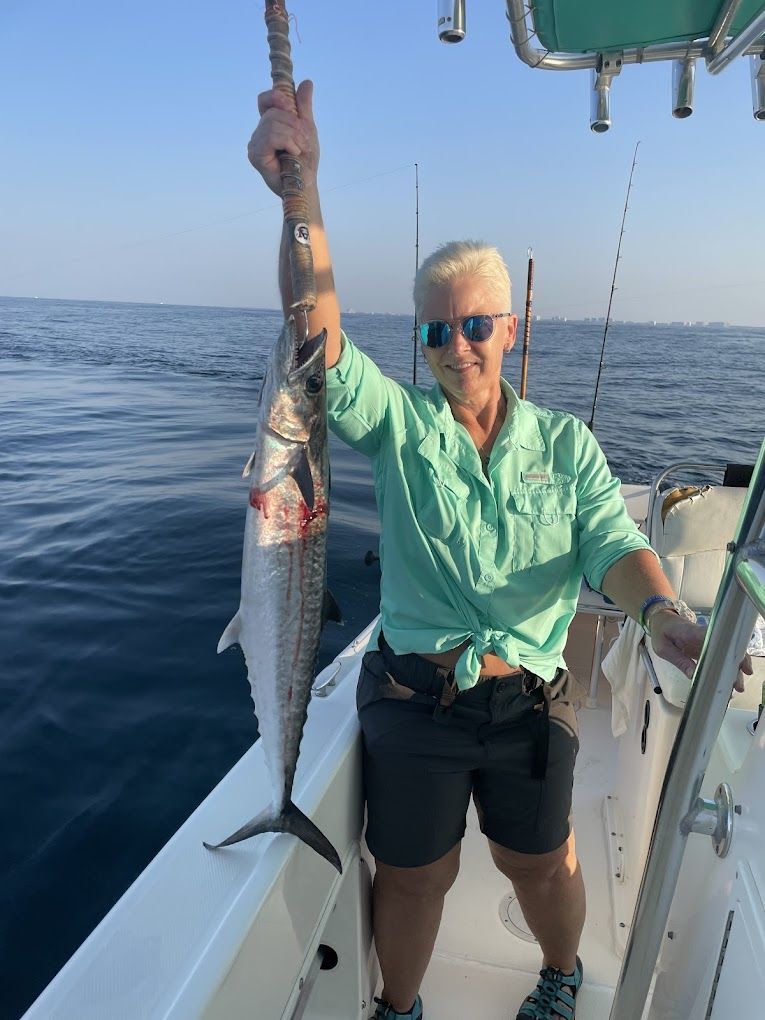 A woman is standing on a boat holding a fish in her hand.