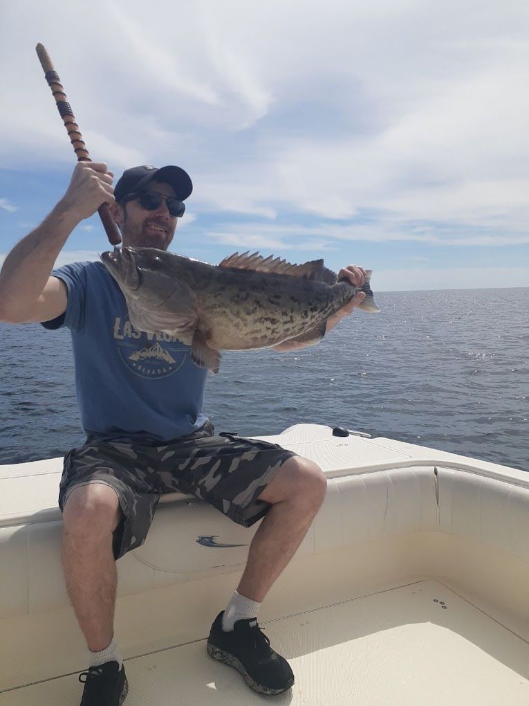 A man is sitting on a boat holding a large fish.