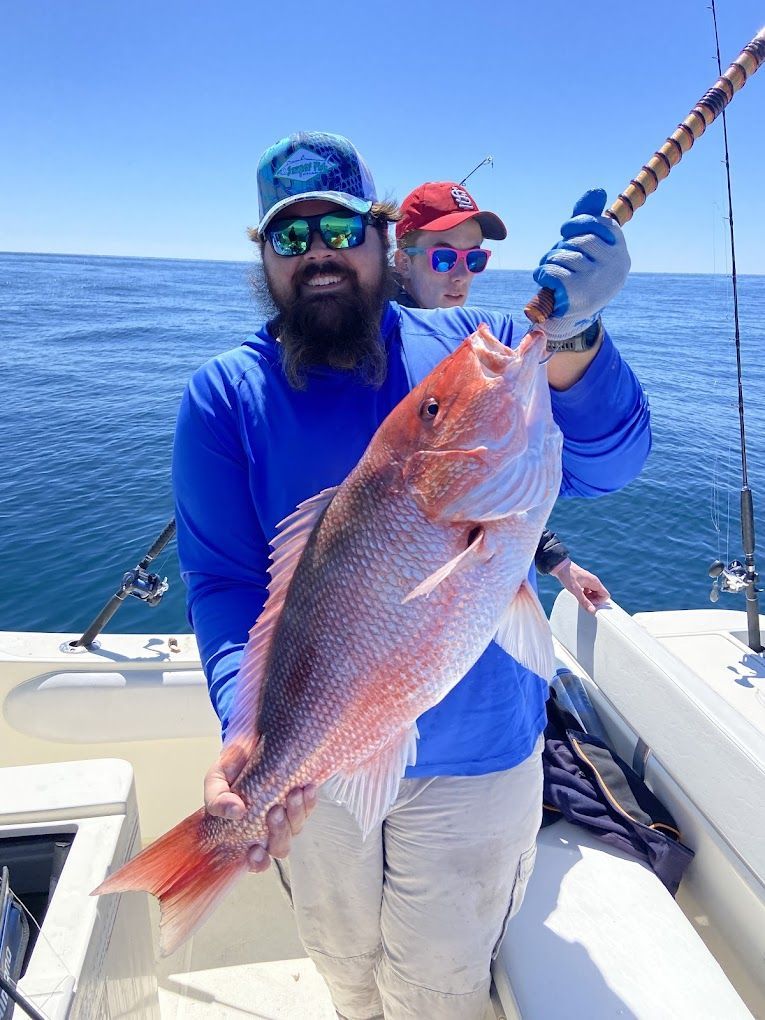 A man is holding a large red fish on a boat.