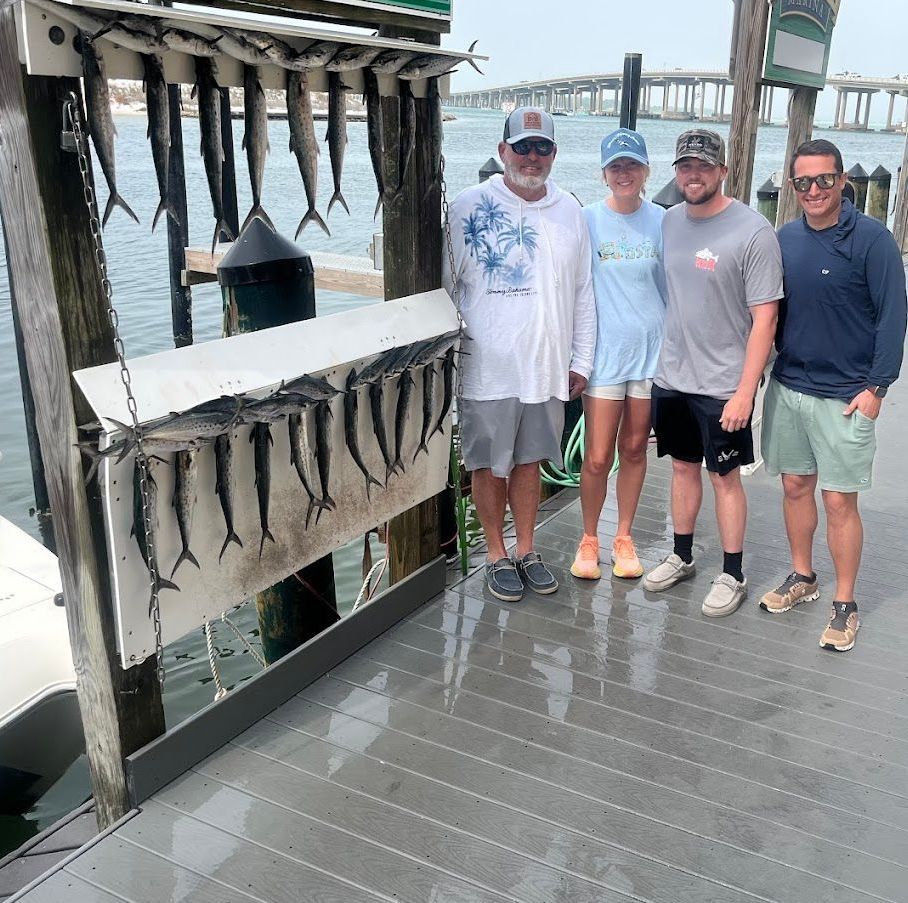A group of people are posing for a picture in front of a display of fish on a dock.