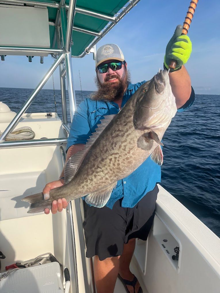 A man is holding a large fish on a boat.