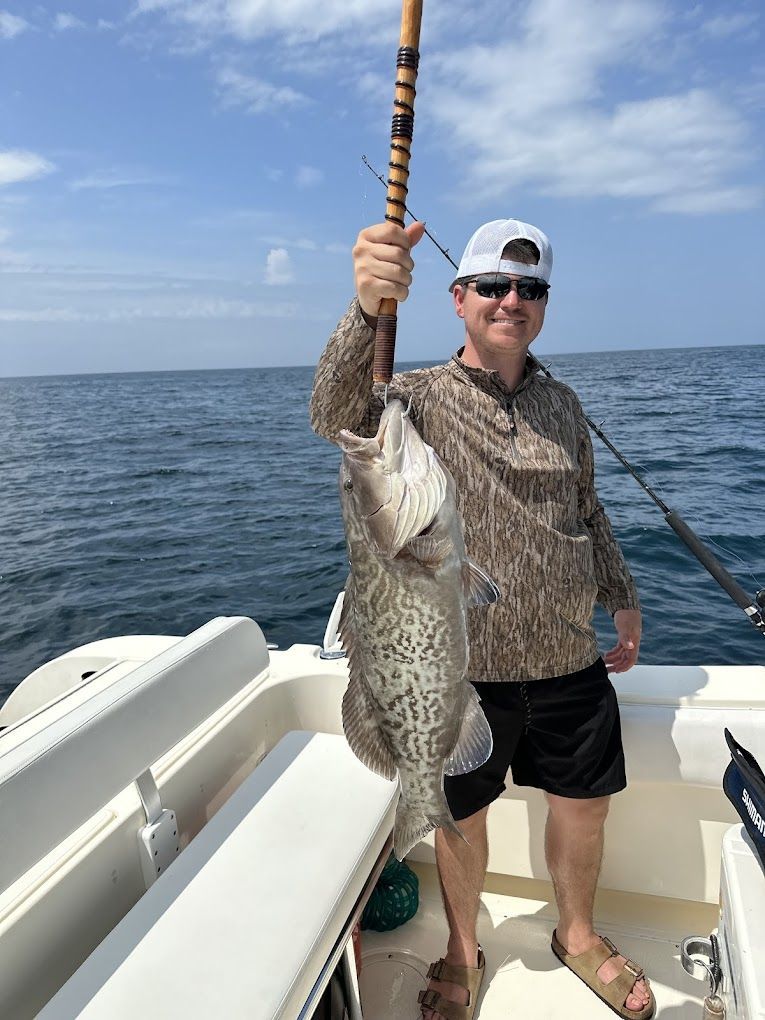 A man is holding a large fish on a boat in the ocean.