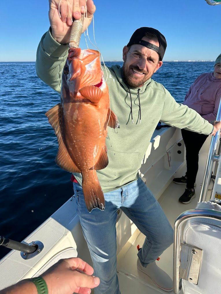 A man is holding a fish on a boat in the ocean.