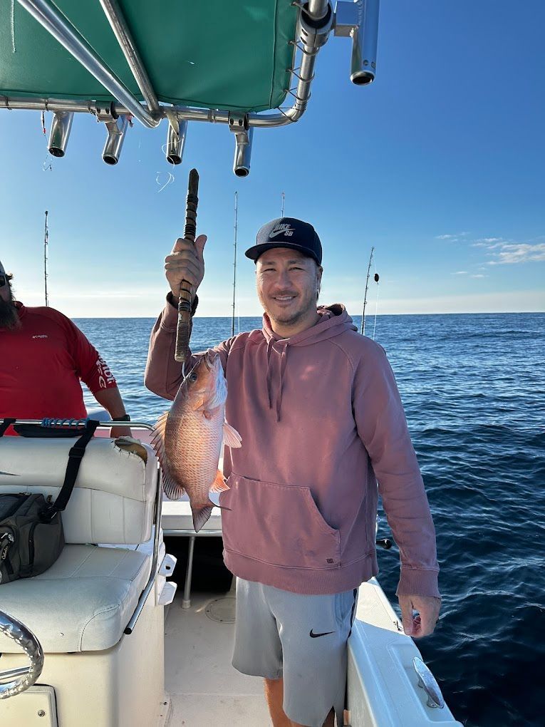 A man is holding a fish on a boat in the ocean.