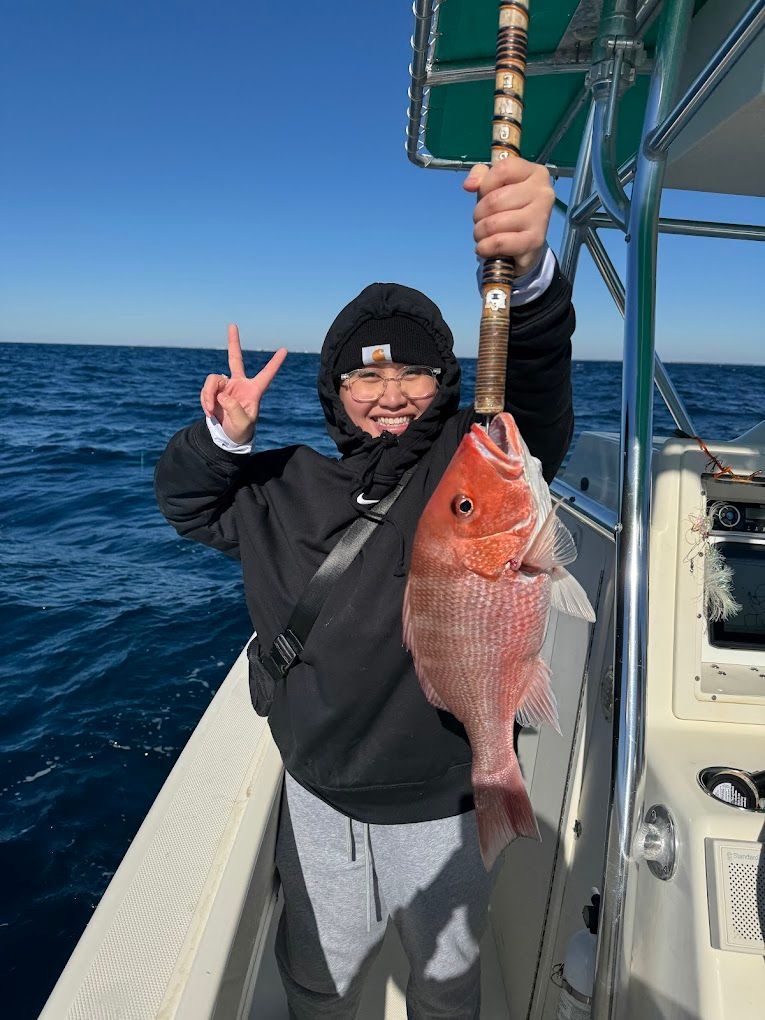 A man is holding a large red fish on a boat.