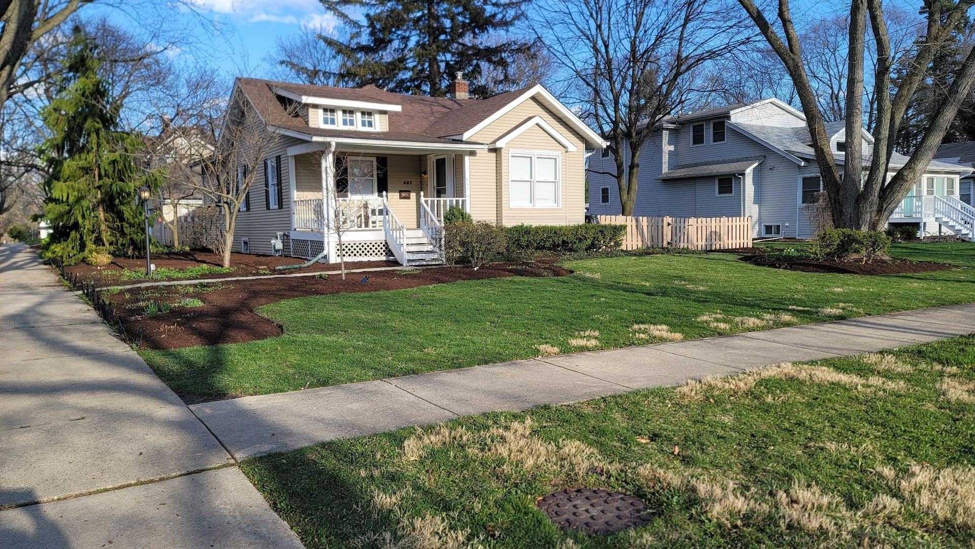 A house with a porch and a sidewalk in front of it.