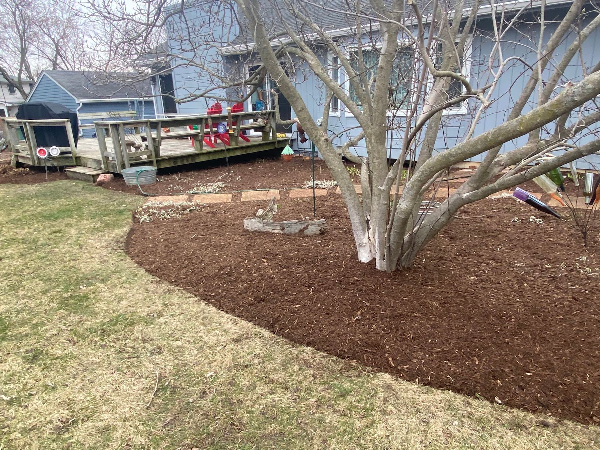 A house with a deck and a tree in front of it.