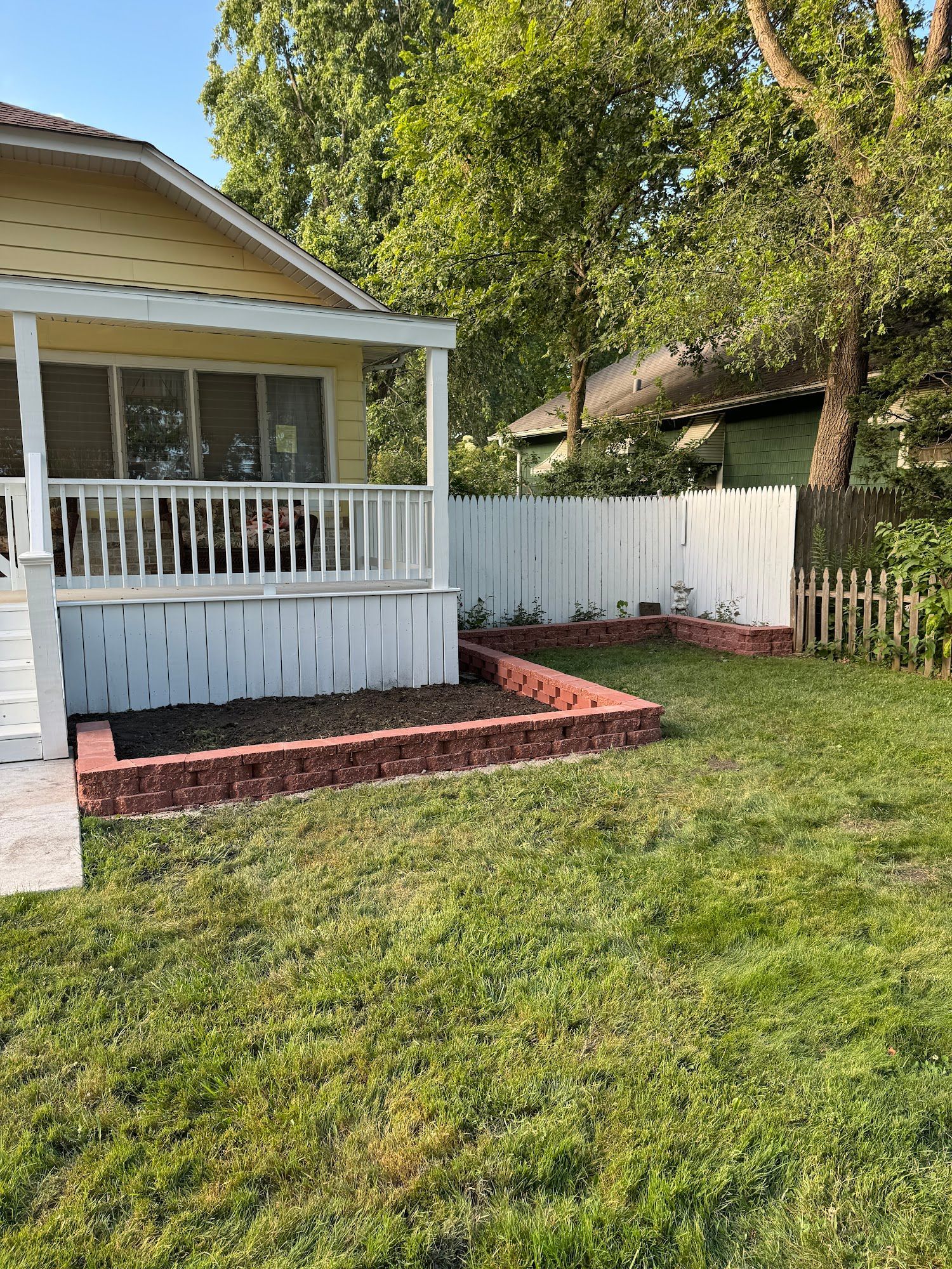 A house with a porch and a white fence in the backyard.