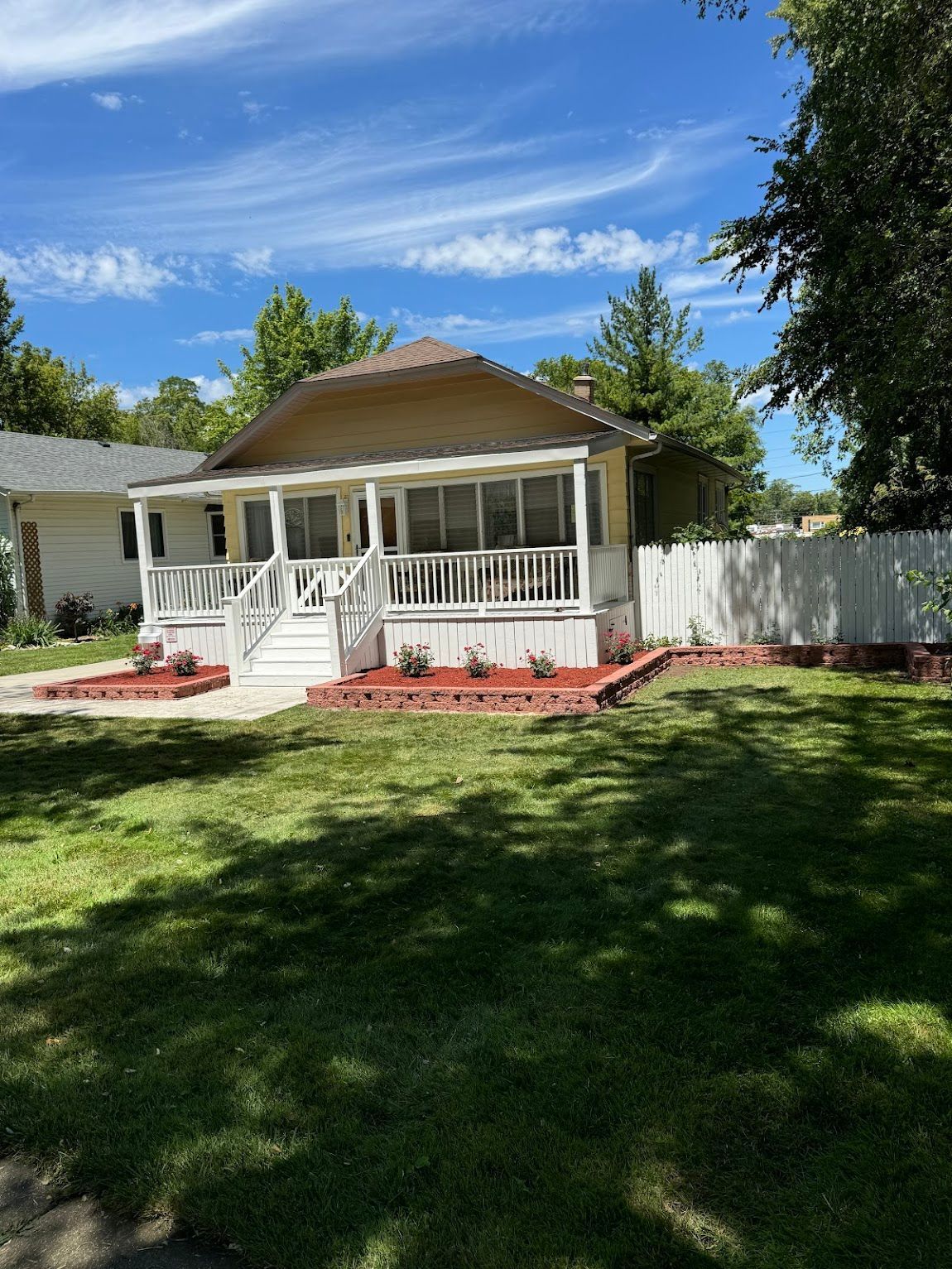 A house with a large porch and a fence in front of it.