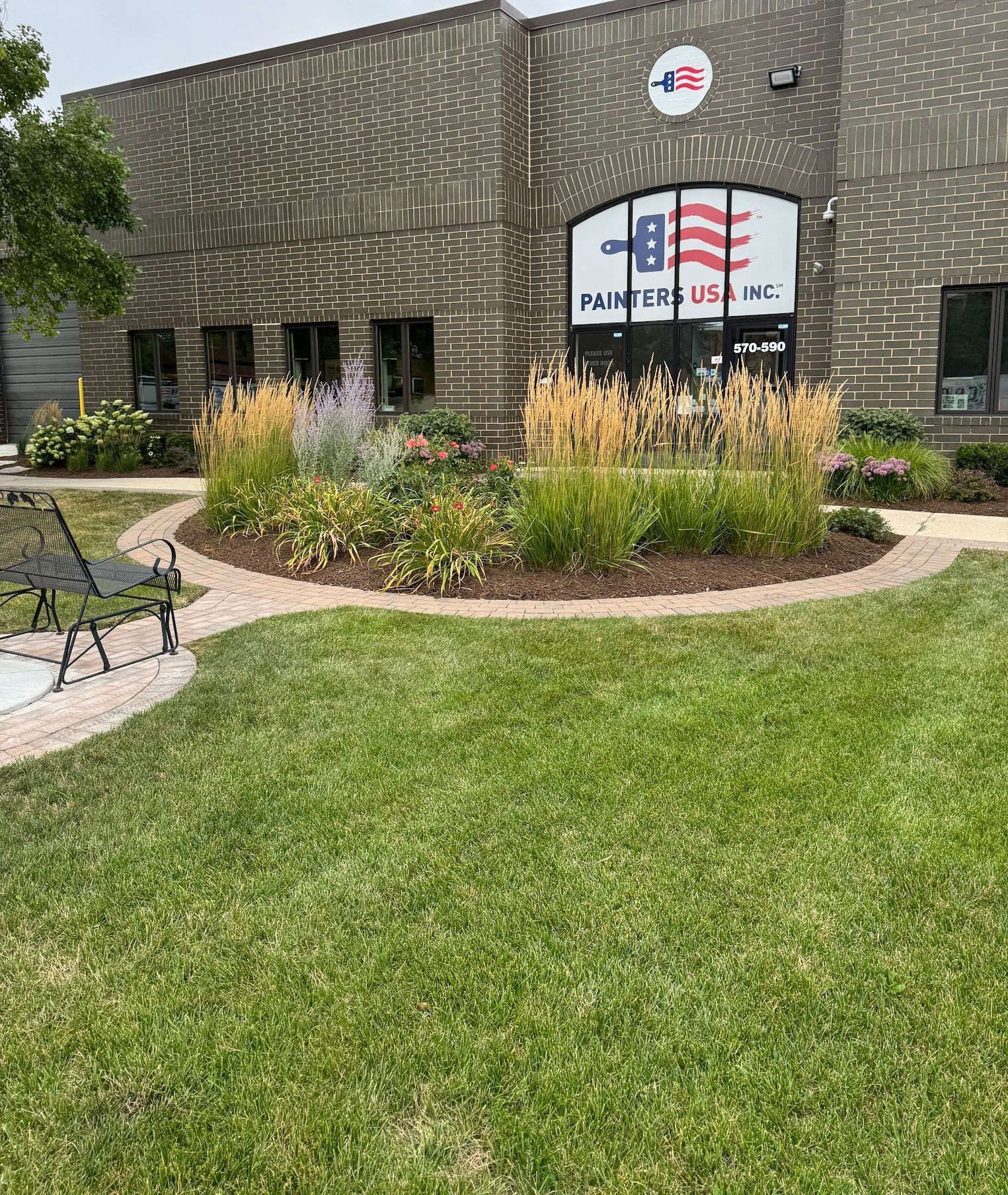 A large brick building with a lush green lawn in front of it.