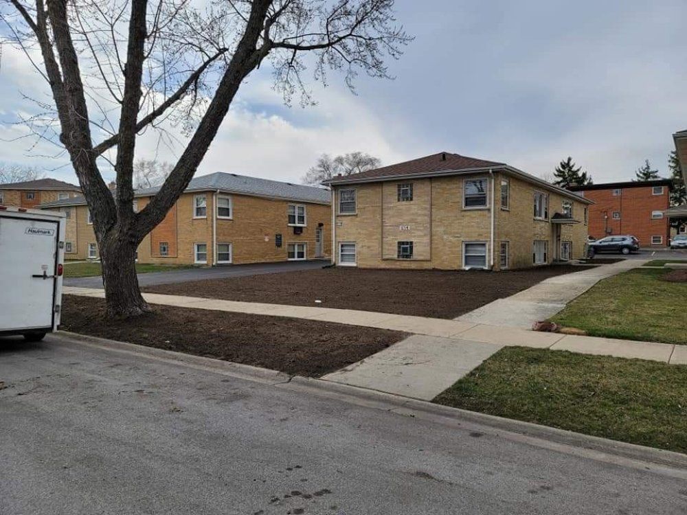 A white trailer is parked in front of a brick apartment building.