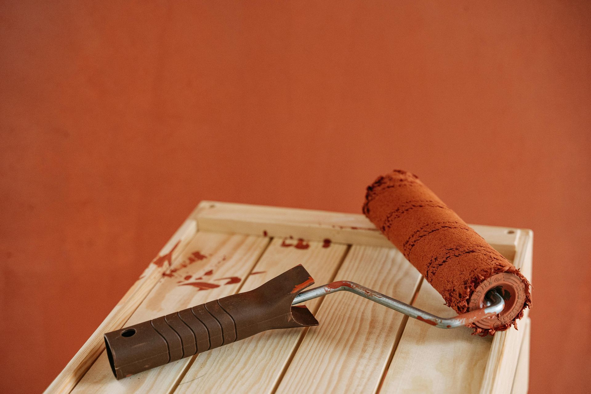 Two paint rollers are sitting on a wooden table.