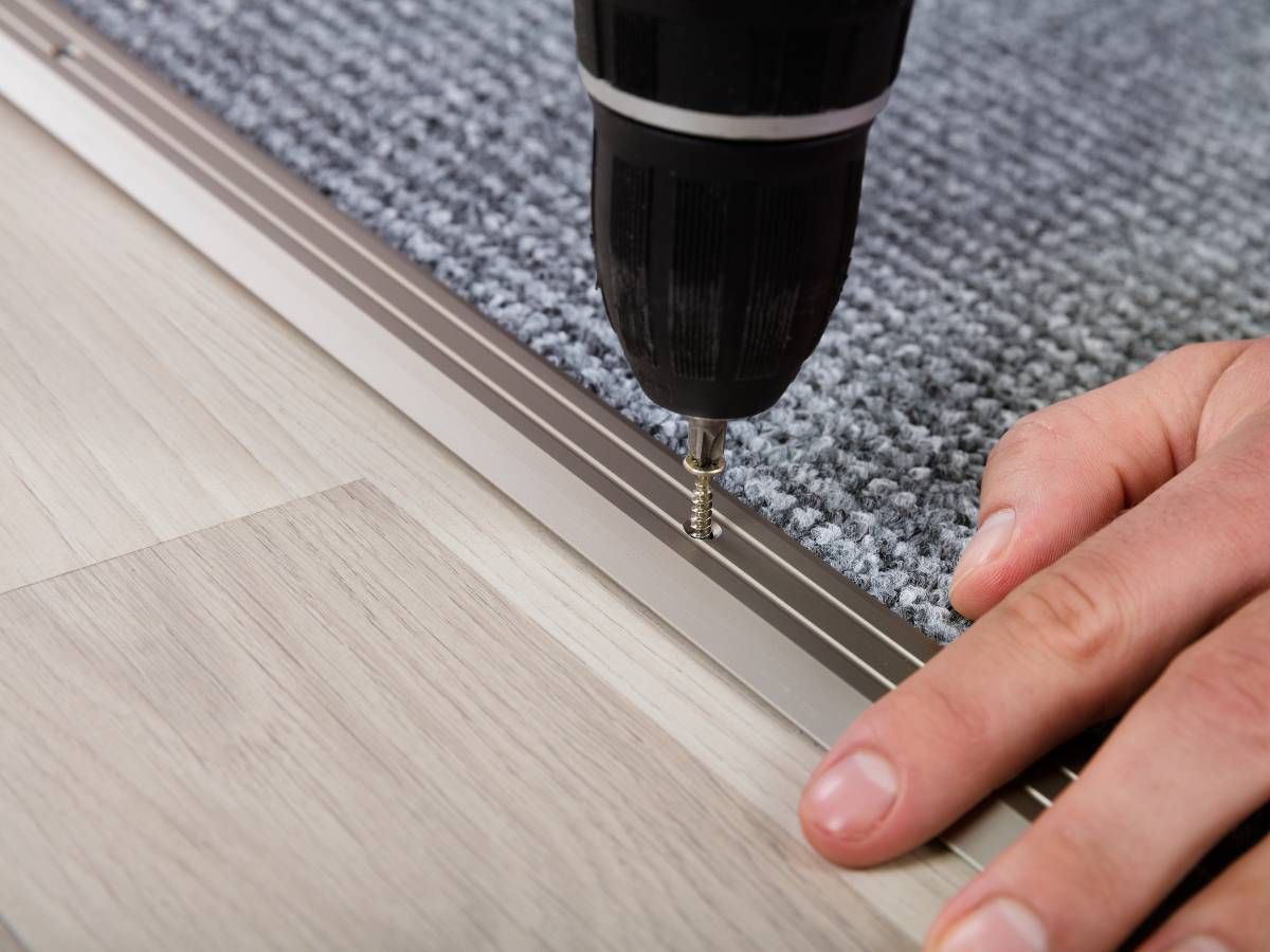Derbyshire Flooring Specialist installing a floor bar between commercial carpet and commercial vinyl flooring office