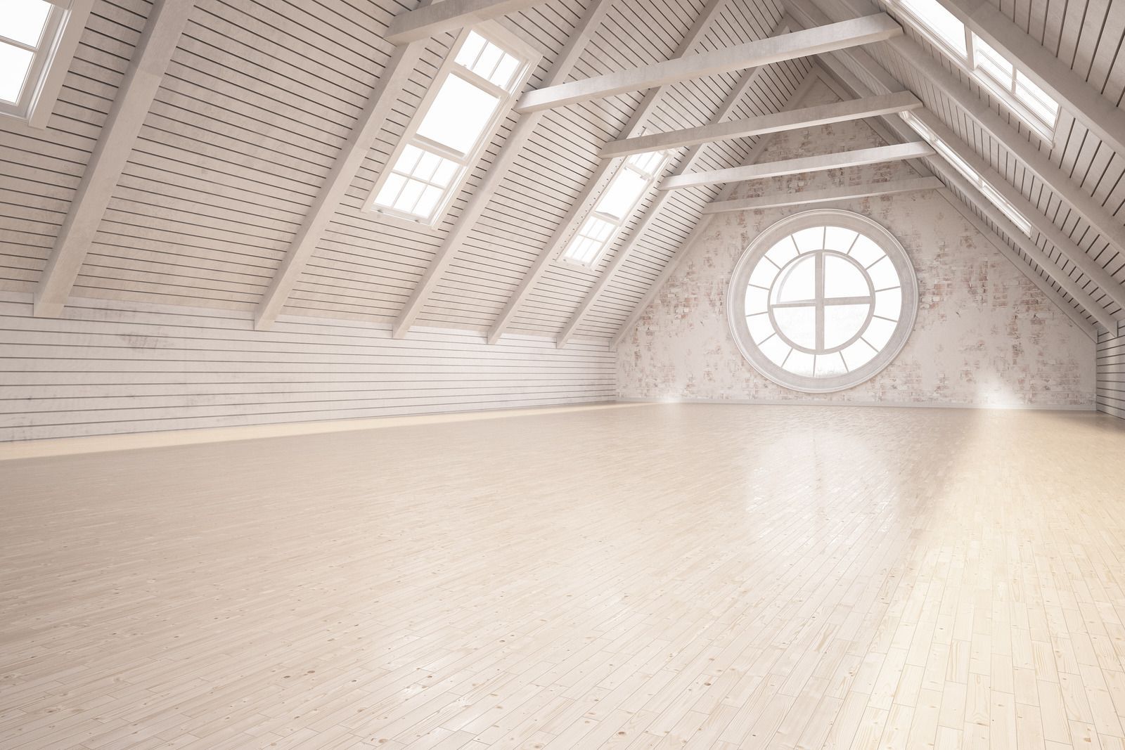 An empty attic with a round window and wooden floors.