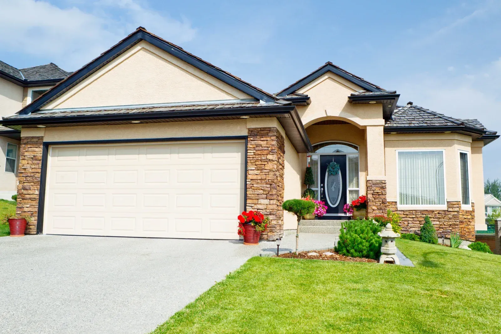 A large house with a large garage door and a lush green lawn.