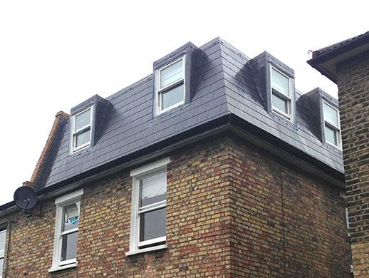 A brick building with a black roof and white windows.